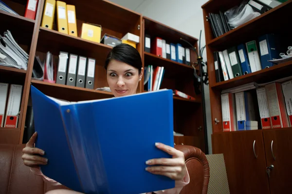 Mujer bonita sorprendida mirando a la carpeta abierta . — Foto de Stock