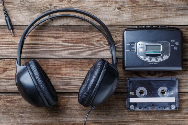 Sluchátka, hráč a retro kompaktní kazeta dřevěná pozadí. Pohled shora — Stock fotografie