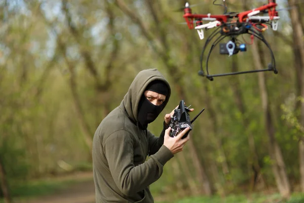 Maskierter Mann bedient Drohne mit Fernbedienung. — Stockfoto
