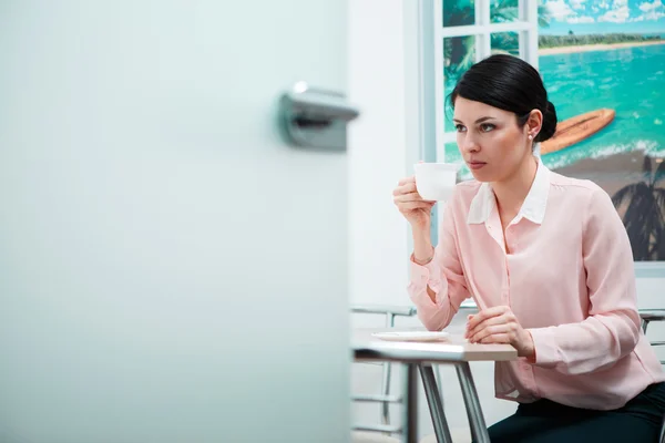 Vrouw koffie drinken in office keuken — Stockfoto