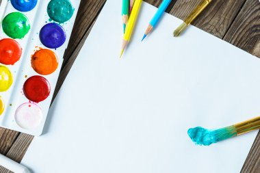 Sanat araçları. Suluboya boya ve fırça ile ahşap arka plan boş beyaz kağıda kapat.