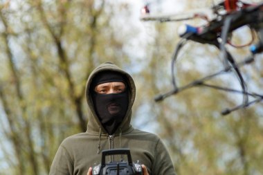 Maskeli adam uzaktan kumandalı bir dron kullanıyor..