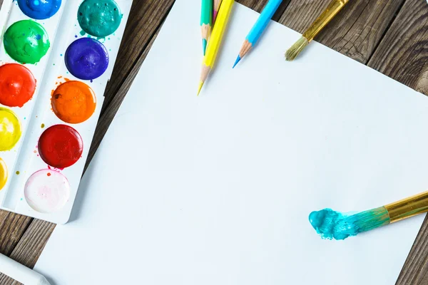 Kunstwerkzeuge. Aquarellfarben und Pinsel mit weißem Papier auf hölzernem Hintergrund in Nahaufnahme. — Stockfoto