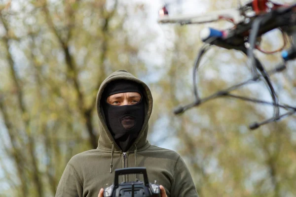 Uomo in maschera che aziona un drone con telecomando. — Foto Stock