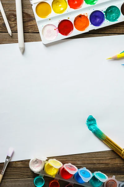 Herramientas de arte. Pinturas y pinceles de acuarela con papel blanco en blanco sobre fondo de madera de cerca . —  Fotos de Stock