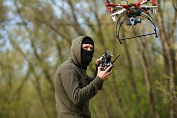 Homem mascarado operando um drone com controle remoto. — Fotografia de Stock