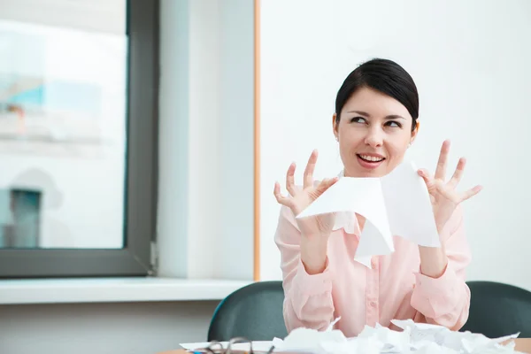 Geschäftsfrau sitzt auf ihrem Schreibtisch und entledigt sich gerne alter Papiere. — Stockfoto