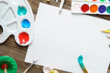 Sanat araçları. Suluboya boya ve fırça ile ahşap arka plan boş beyaz kağıda kapat.