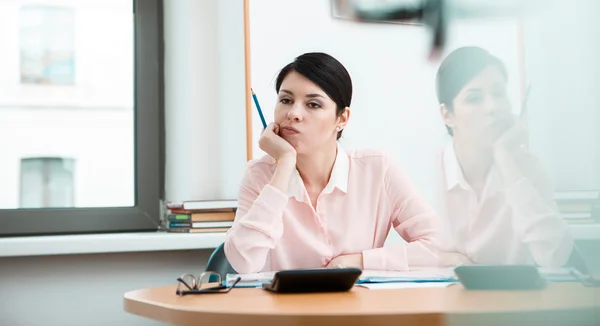 Jeune employée de bureau rêvant dans son lieu de travail — Photo