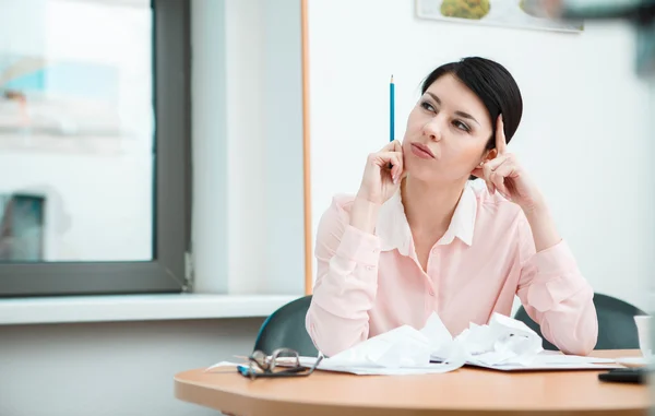 Businesswoman sitting at desk in the office in thoughts. — Stock Photo, Image