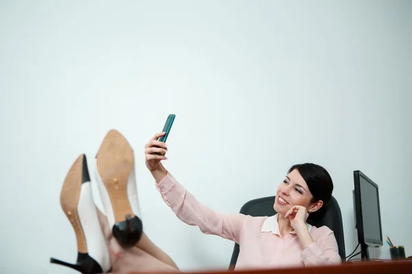 Relajada mujer de negocios sentada en una silla con piernas sobre la mesa. — Foto de Stock