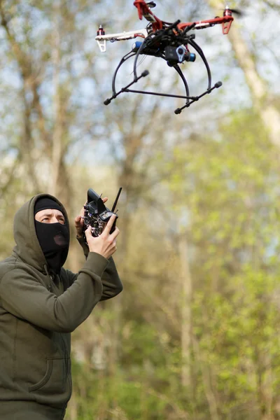 Homem mascarado operando um drone com controle remoto. — Fotografia de Stock