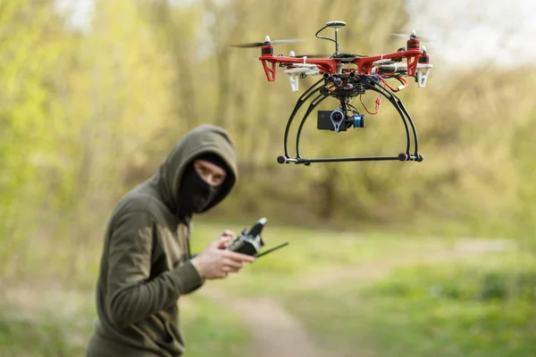 Maskierter Mann bedient Drohne mit Fernbedienung. — Stockfoto