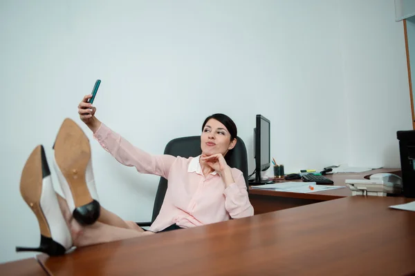 Femme d'affaires détendue assise sur une chaise avec des jambes sur la table. — Photo