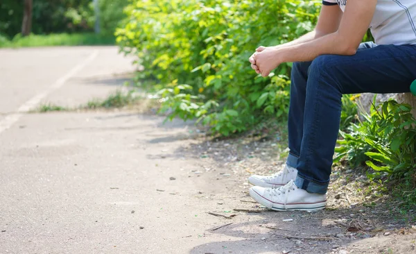 Young man sitting wearing jeans outdoor. — Stock Photo, Image