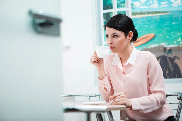 Woman drinking coffee in office kitchen — Stock Photo, Image