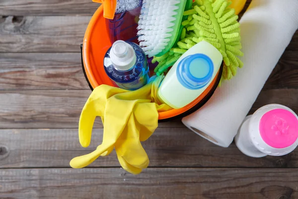 Secchio di plastica con prodotti per la pulizia su fondo legno — Foto Stock