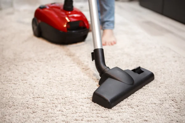 Maid cleaning carpet with modern red vacuum cleaner — Stock Photo, Image