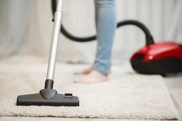 Wanita membersihkan karpet dengan vacuum cleaner — Stok Foto