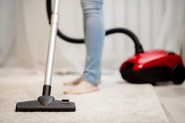 Mulher fazendo limpeza em casa, aspirando tapete com pilha grossa — Fotografia de Stock