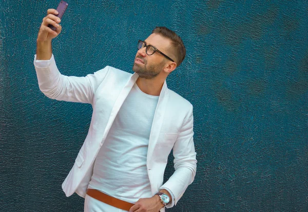 Ung man i vita kläder tar selfie, eleganta porträtt — Stockfoto