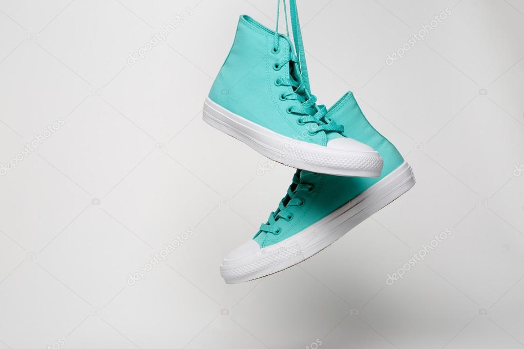 Blue Sport shoes hanging on laces on white background