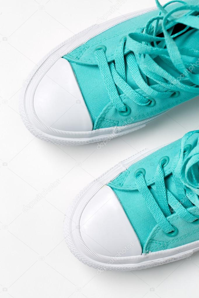 Top view of turquoise sneakers on white background.