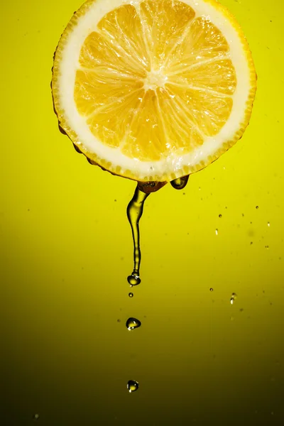 Splash juice med citron skiva isolerad på gul bakgrund — Stockfoto