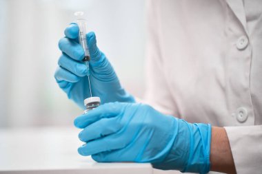 Doktor aşıyı şırıngaya çeviriyor.