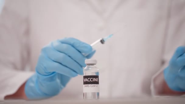 医生手紧握蓝色防护手套，将疫苗从药瓶注入注射器 — 图库视频影像