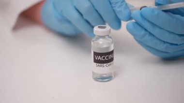 Doktorun ellerini mavi ile kapat koruyucu eldivenler aşıyı şişeden şırıngaya doldurur.