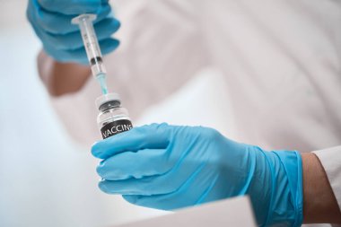 Doktor aşıyı şırıngaya çeviriyor.