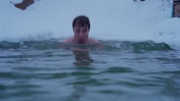 Junger Mann schwimmt im Winterfluss — Stockvideo