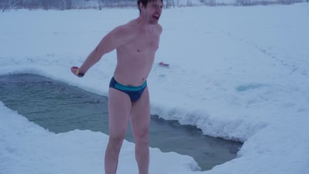 Young man jumping to keep warming after swimming at ice river — Stock Video