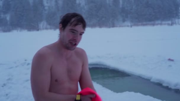 Człowiek wyciera się ręcznikiem po kąpieli w lodowej rzece. — Wideo stockowe