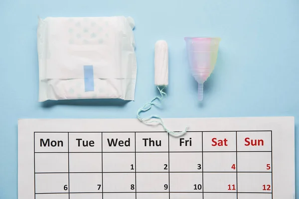 Calendario con tampones de algodón y copa menstrual. Días críticos para la mujer y protección de la higiene — Foto de Stock