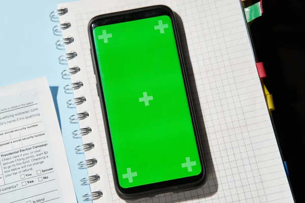 Mobilní telefon se zelenou obrazovkou přes notepad s warky a 1040 daňové formuláře — Stock fotografie