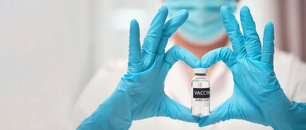 Medici mano in guanti medici sterili che mostrano la forma del cuore con il vaccino COVID-19 — Foto Stock