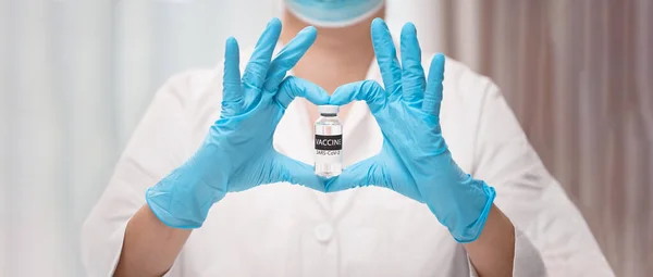 Medici mano in guanti medici sterili che mostrano la forma del cuore con il vaccino COVID-19 — Foto Stock