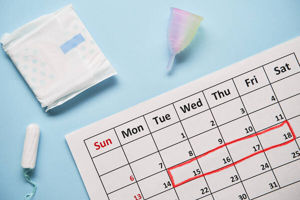 Calendar with cotton tampons and menstrual cup. Woman critical days and hygiene protection