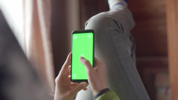 Młoda kobieta w domu lyung i używać smartfona z zielonym ekranem. Zdjęcia z kamery w punkcie widzenia. — Wideo stockowe