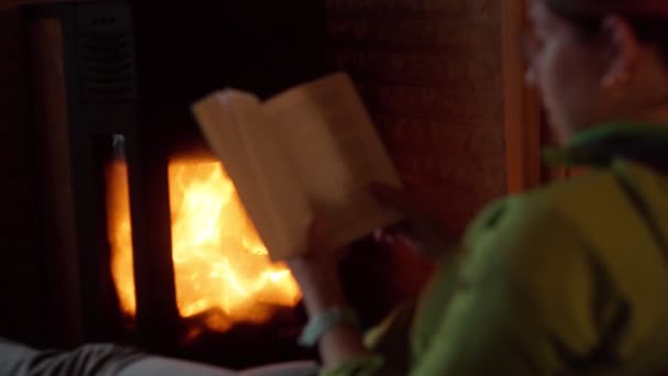 집 벽난로 근처에서 책을 읽고 있는 젊은 여자. — 비디오
