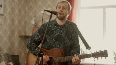 Gitar çalan ve prova sırasında şarkı söyleyen adam.