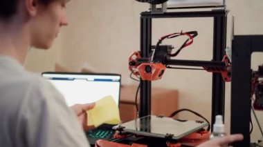 Kullanmadan önce 3D yazıcıyı temizleyen adam