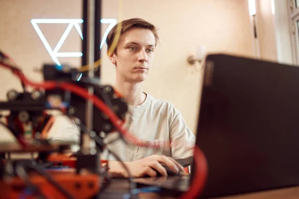 Молодой человек работает за ноутбуком. Концепция 3D печати — стоковое фото