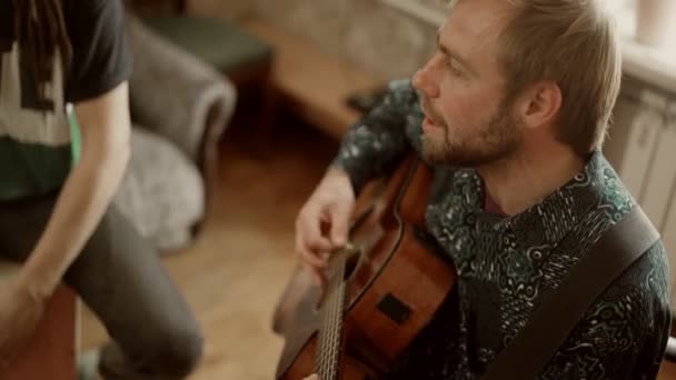 Мужчина-музыкант играет на гитаре и поет рядом с другом — стоковое видео