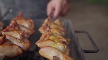 Şişte tavuk kanadı pişiren bir adam. Sığ dof ile Hd yavaş çekim yakın çekim