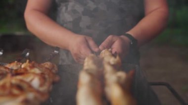 Şişte tavuk kanadı pişiren bir adam. Sığ dof ile Hd yavaş çekim yakın çekim