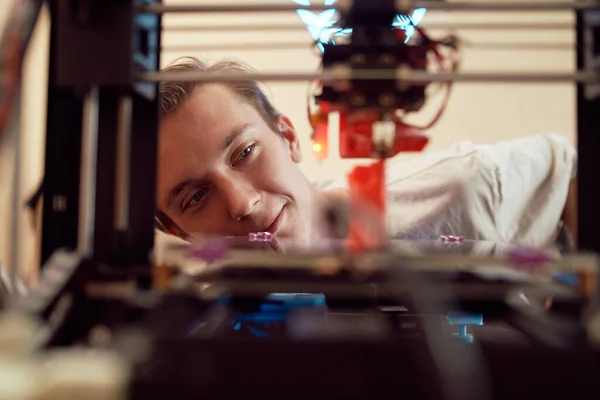Iloinen nuori mies katsomassa 3D tulostus prosessi — kuvapankkivalokuva