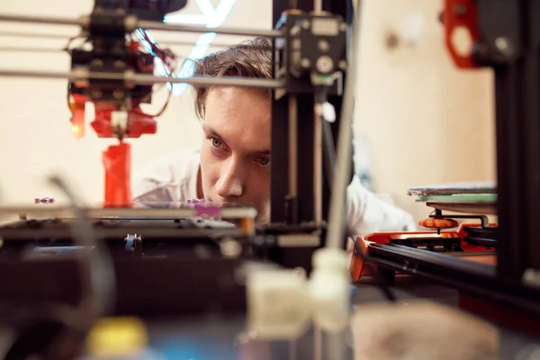 Joven macho mirando la impresora 3D — Foto de Stock